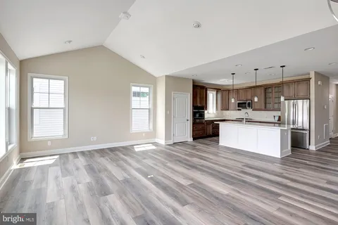 a large kitchen with a refrigerator a sink dishwasher a stove and white cabinets with wooden floor