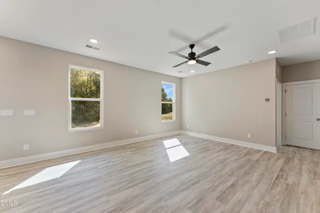 an empty room with wooden floor and windows
