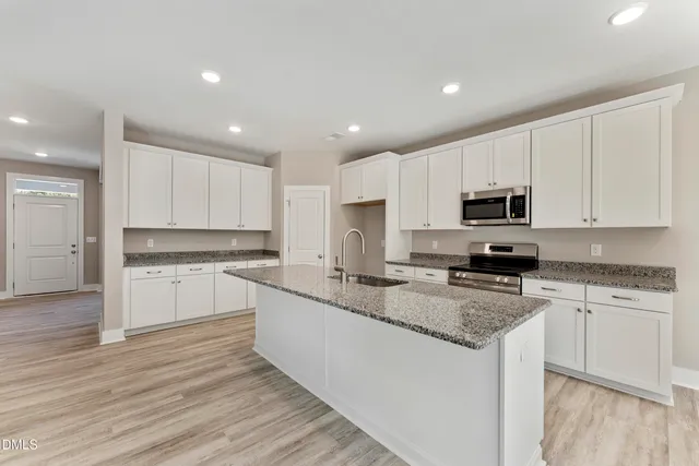 a kitchen with granite countertop white cabinets and white appliances