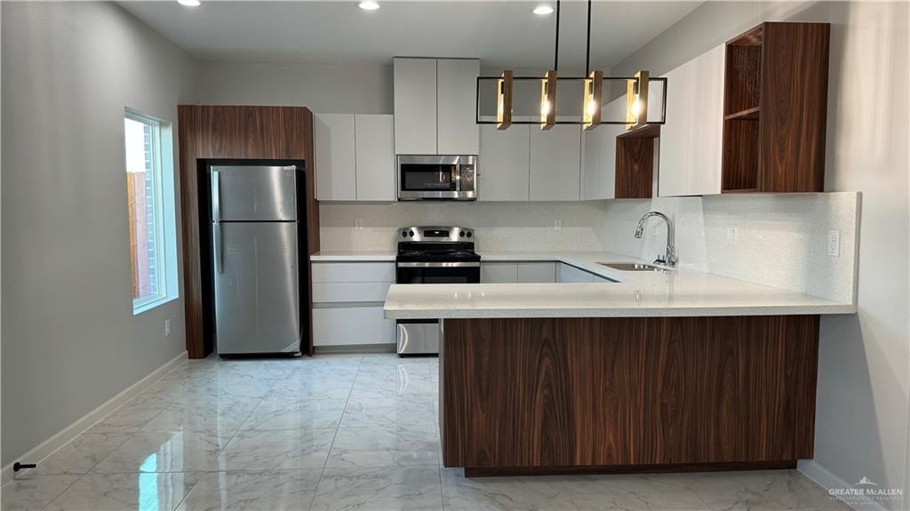 906 Hidden Hills St Mission, Unit 3 Mission, TX 78572 - Photo 4 of 10 Kitchen with tasteful backsplash, white cabinetry, sink, decorative light fixtures, and appliances with stainless steel finishes