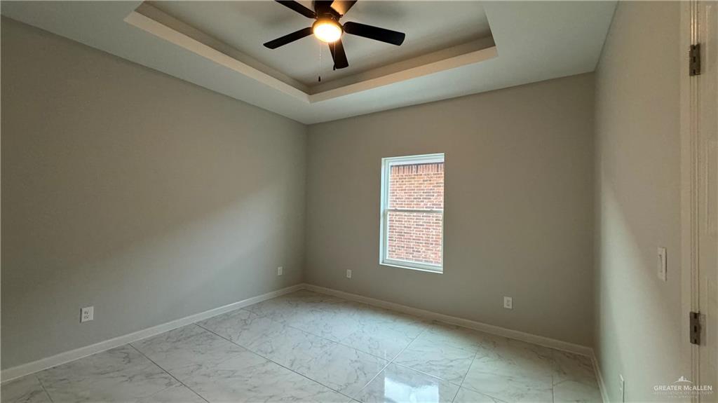 906 Hidden Hills St Mission, Unit 3 Mission, TX 78572 - Photo 7 of 10 Tiled empty room featuring ceiling fan and a tray ceiling