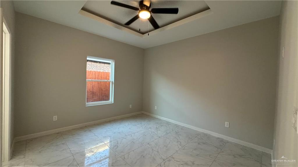 906 Hidden Hills St Mission, Unit 3 Mission, TX 78572 - Photo 9 of 10 Empty room featuring a tray ceiling, light tile floors, and ceiling fan
