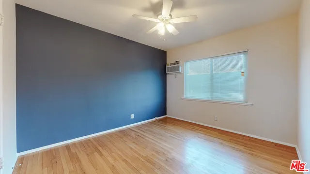 an empty room with a fan & a window