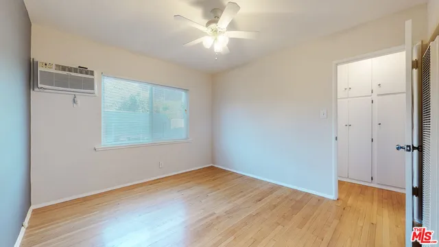 a view of an empty room with window and wooden floor