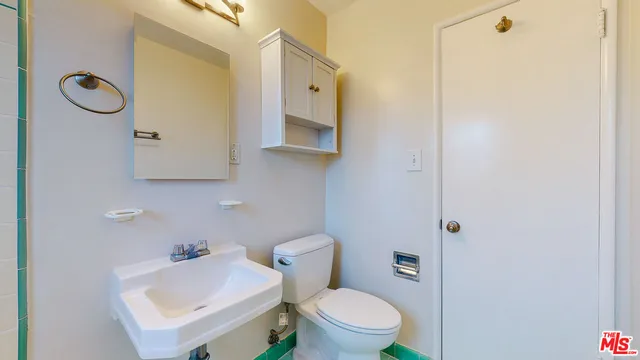 a bathroom with a toilet a sink and mirror