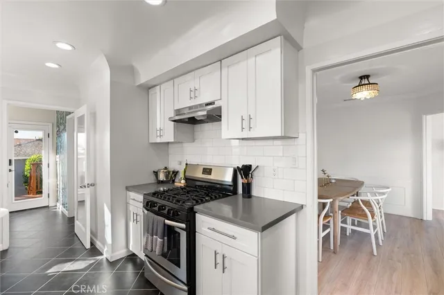 a kitchen with stainless steel appliances granite countertop a stove a refrigerator and a white cabinets with wooden floor