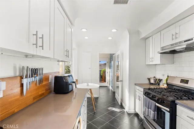 a kitchen with stainless steel appliances granite countertop a stove a refrigerator a sink dishwasher and white cabinets with wooden floor