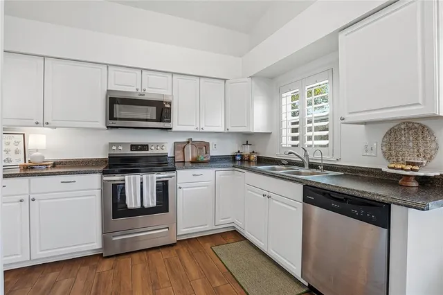 a kitchen with granite countertop a sink stainless steel appliances and white cabinets