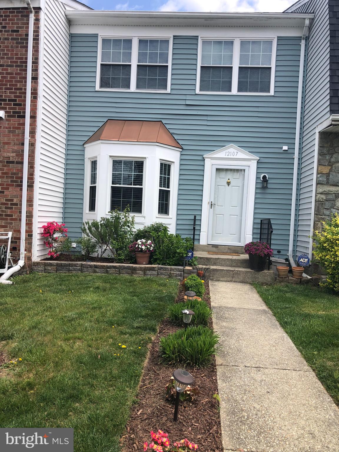 a front view of house and yard with beautiful flowers
