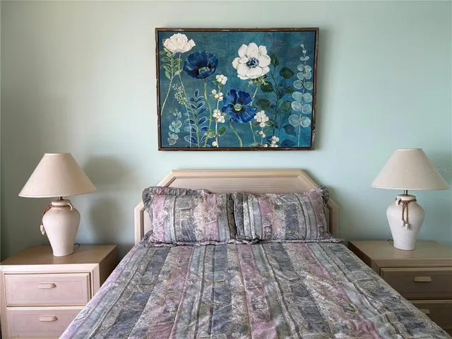 a bedroom with a bed and a lamp on dresser