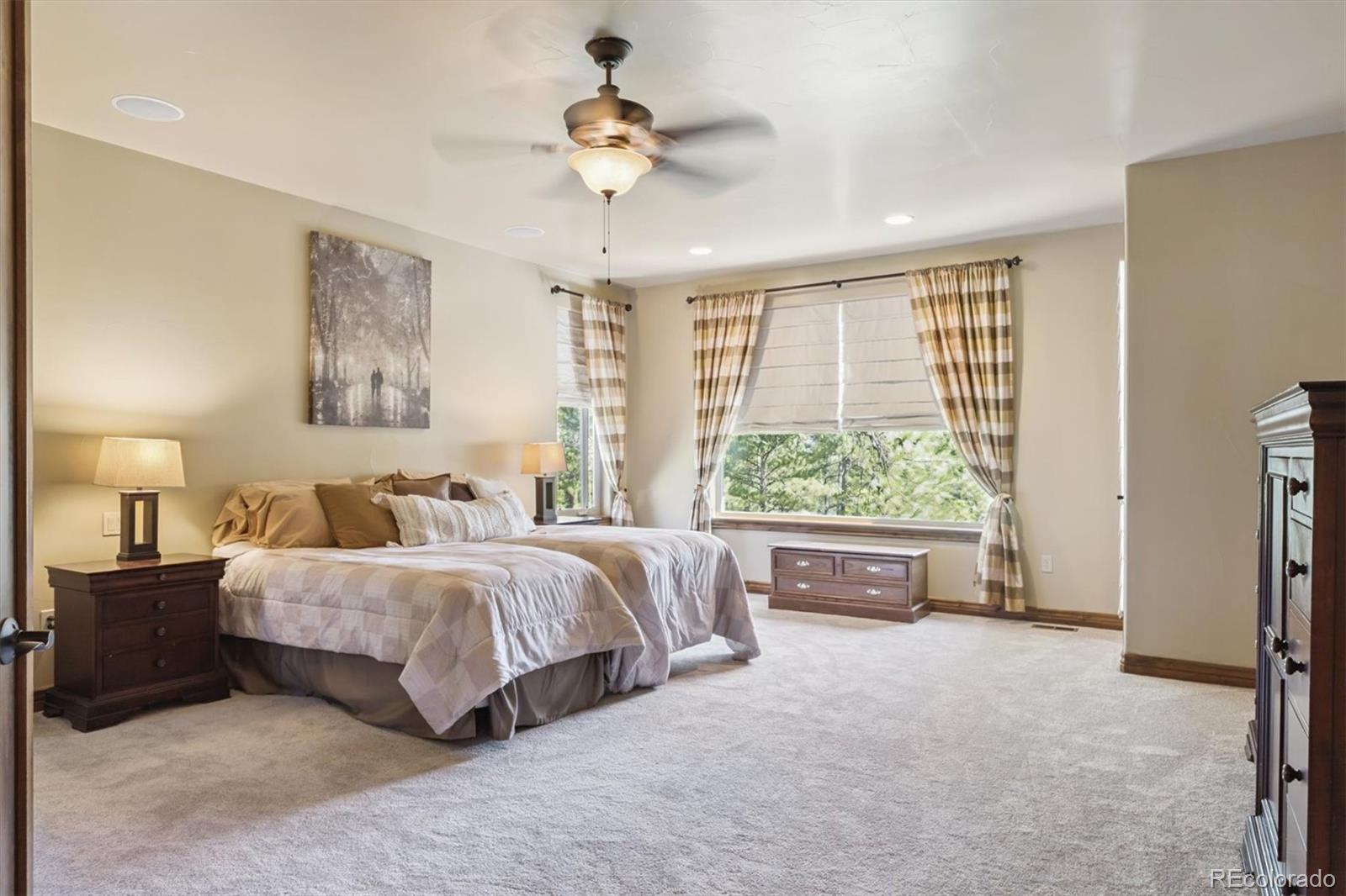 7994 Monarch Road Larkspur, CO 80118 - Photo 14 of 48 a spacious bedroom with a large bed and a chandelier