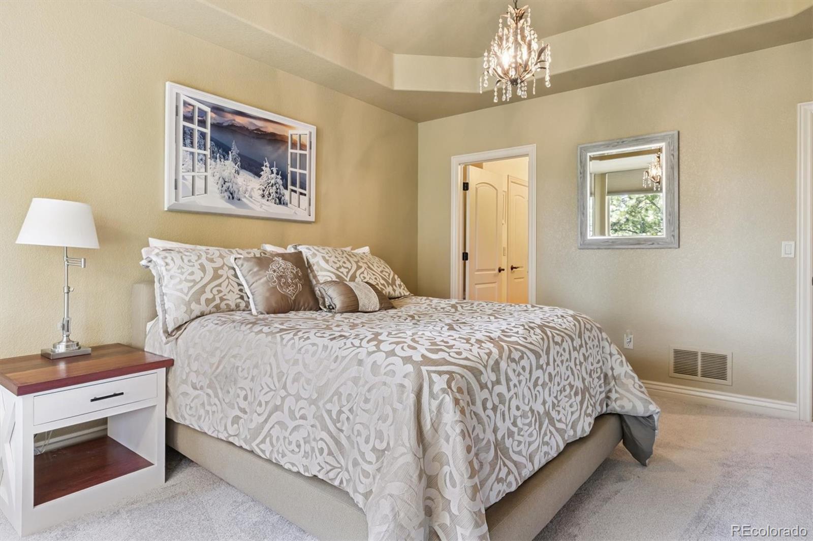 7994 Monarch Road Larkspur, CO 80118 - Photo 30 of 48 a bedroom with a large bed and a chandelier