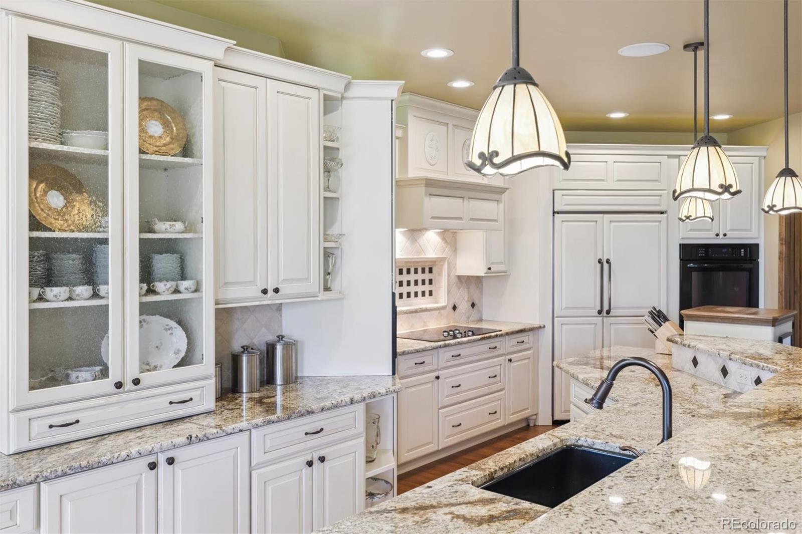7994 Monarch Road Larkspur, CO 80118 - Photo 9 of 48 a kitchen with stainless steel appliances kitchen island granite countertop a stove a sink and white cabinets with wooden floor