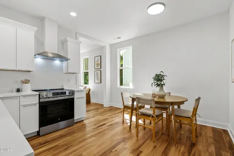 a kitchen with granite countertop a dining table chairs stove and white cabinets
