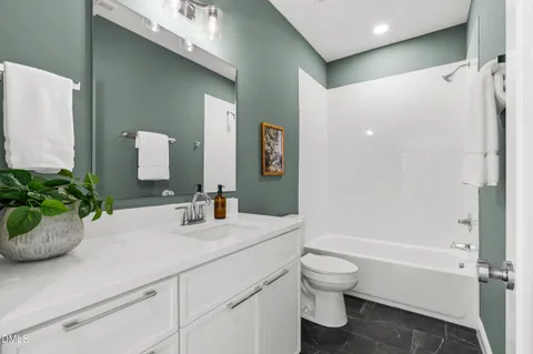 a bathroom with a granite countertop sink a toilet and a large mirror