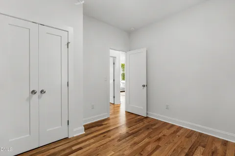 a view of an empty room with wooden floor and closet