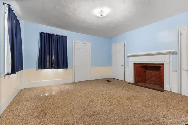 a view of an empty room with window and a fireplace