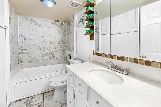 a bathroom with a granite countertop sink a toilet and shower