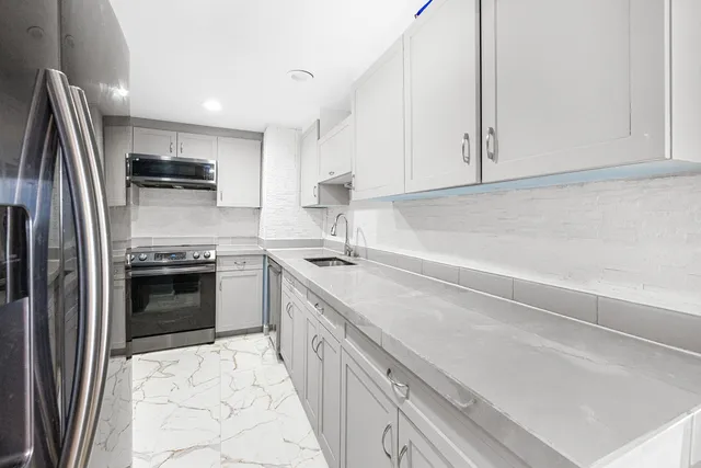 a kitchen with granite countertop a sink stainless steel appliances and cabinets
