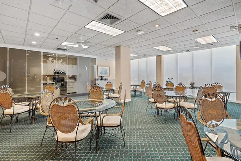 a room with lots of chairs a desk and a chandelier