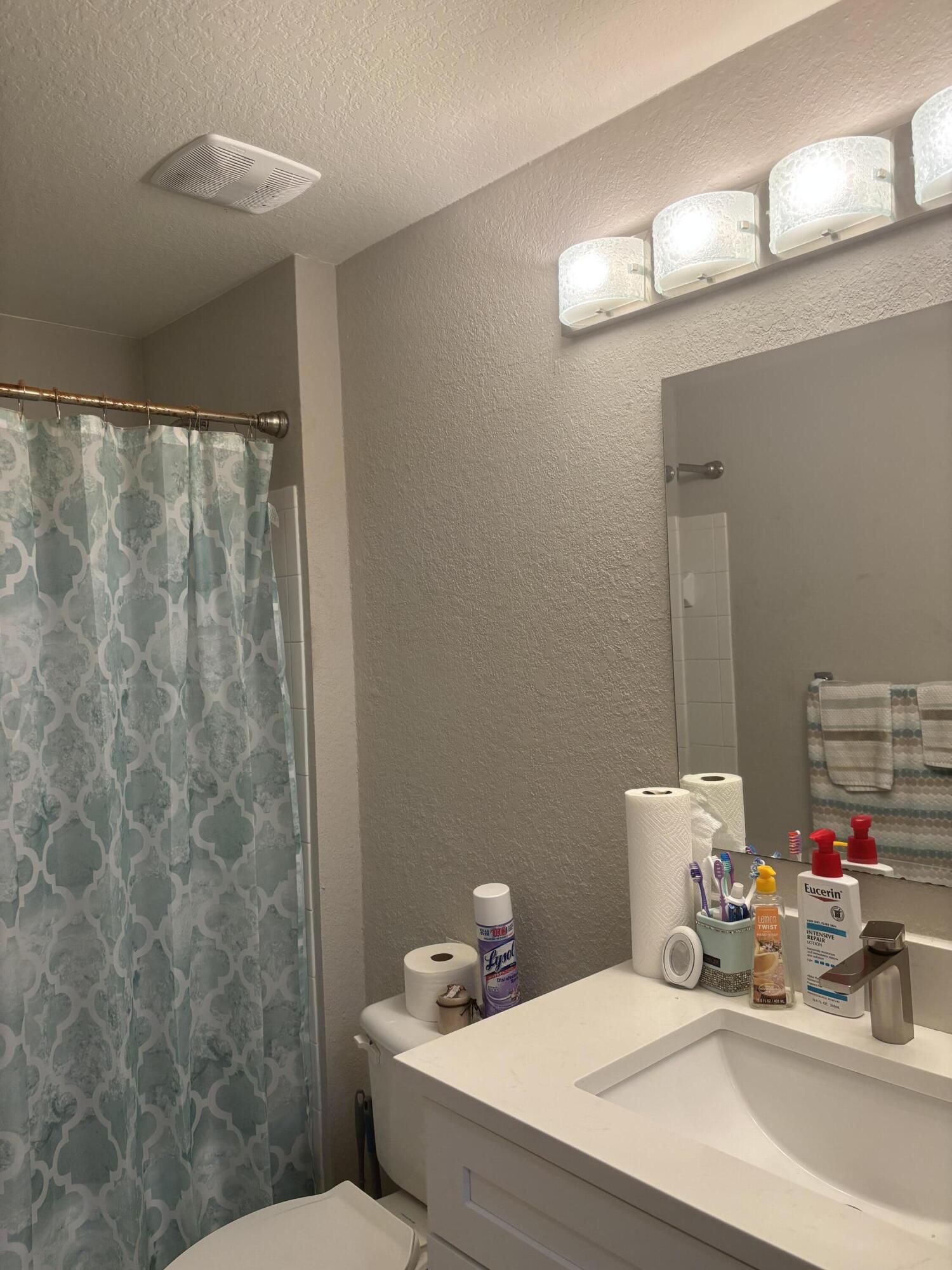 350 Crestwood Circle, Unit 106 Royal Palm Beach, FL 33411 - Photo 19 of 28 a bathroom with a sink a toilet and a mirror