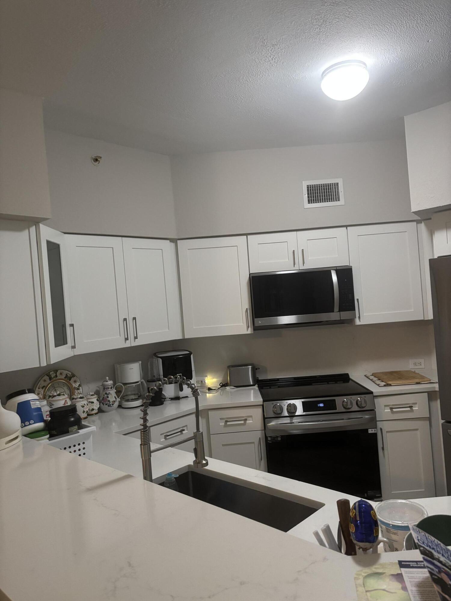 350 Crestwood Circle, Unit 106 Royal Palm Beach, FL 33411 - Photo 28 of 28 a kitchen with a sink and a stove top oven