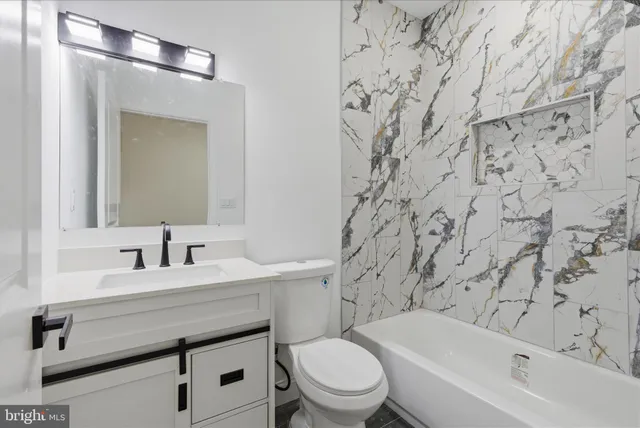 a bathroom with a toilet sink vanity tub and mirror