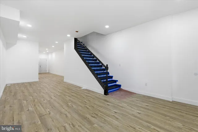 a view of an empty room with wooden floor and stairs
