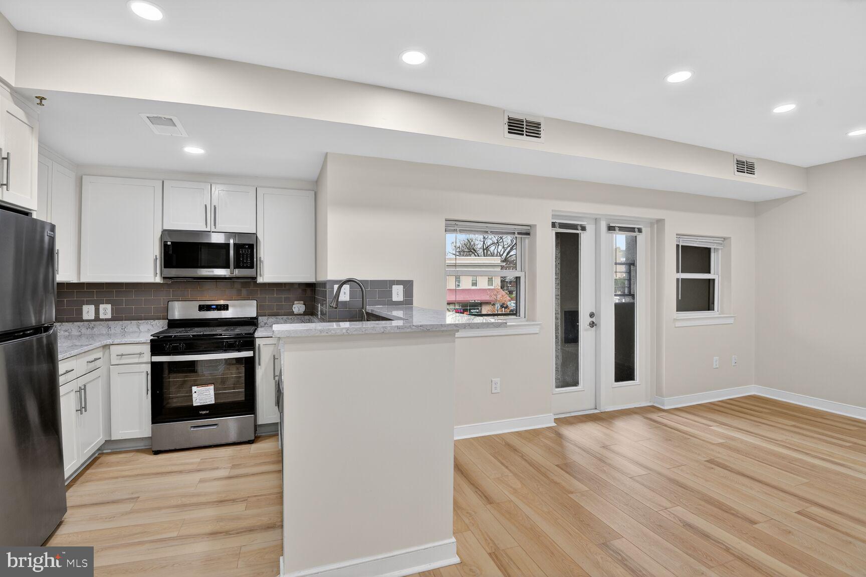4800 Georgia Avenue Northwest, Unit 205 Washington, DC 20011 - Photo 5 of 15 a kitchen with granite countertop stainless steel appliances and wooden cabinets