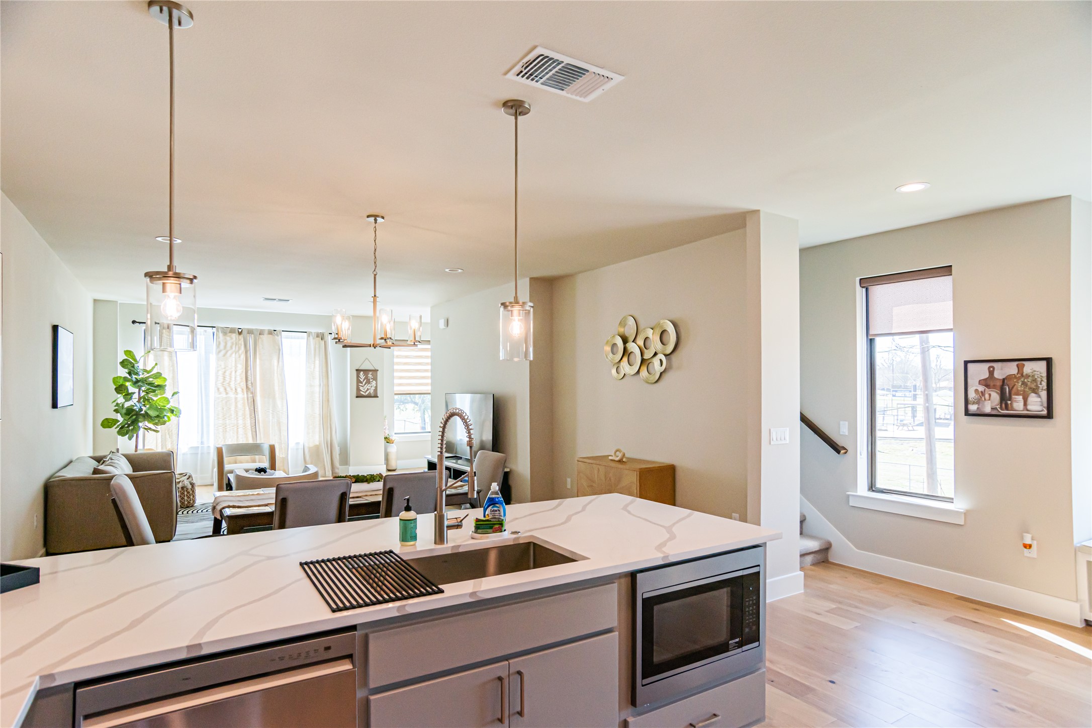 13309 Morris Road, Unit 11 Austin, TX 78729 - Photo 8 of 31 A pristine quartz-topped kitchen island with an integrated microwave anchors this open-concept living space, illuminated by modern pendant lighting.