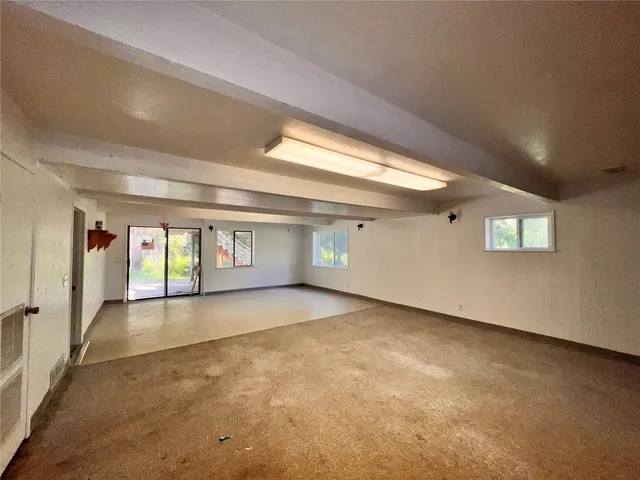 a view of an empty room with window and stairs