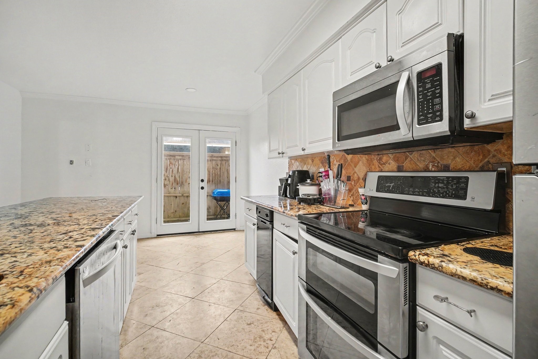 5801 Lumberdale Road, Unit 78 Houston, TX 77092 - Photo 11 of 35 Bright and inviting kitchen with sleek stainless steel appliances, elegant granite countertops, and ample cabinetry, seamlessly opening to a charming outdoor space through French doors.