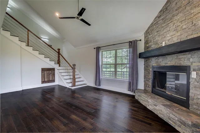 an empty room with wooden floor fireplace and windows