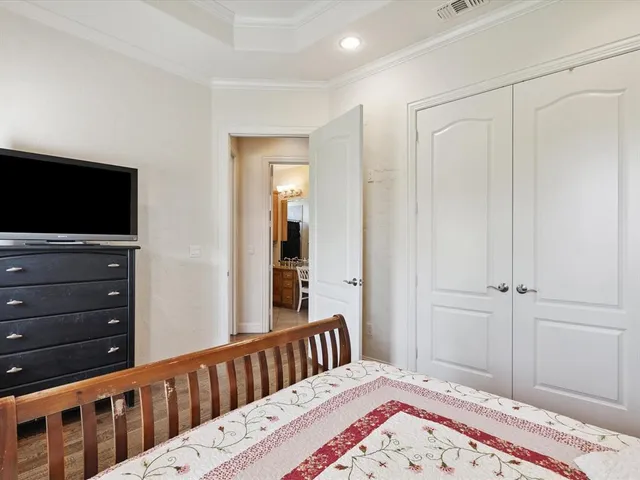 a bedroom with a bed and a flat tv screen on dresser