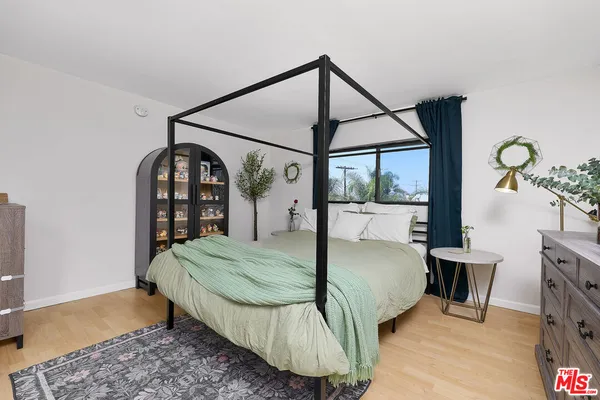 a bedroom with a bed window and a wooden floor