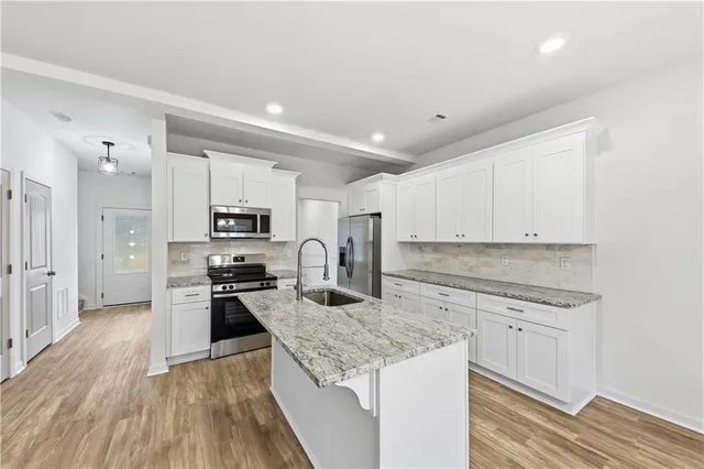 a kitchen with stainless steel appliances granite countertop a stove top oven a sink and dishwasher a refrigerator with wooden floor