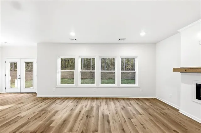 an empty room with wooden floor and windows