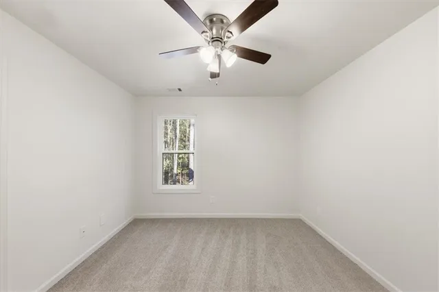 an empty room with a window and a ceiling fan