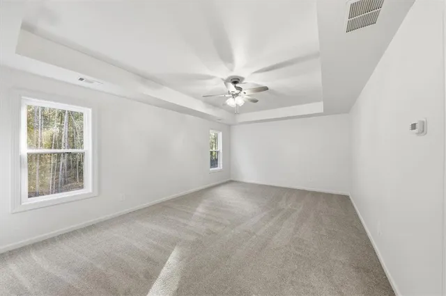 an empty room with windows and chandelier fan