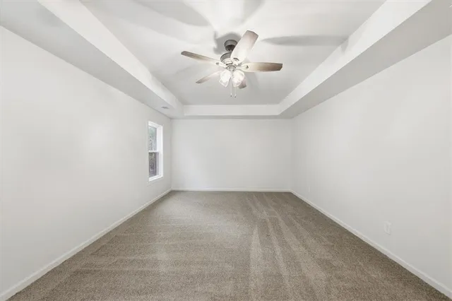 an empty room with chandelier fan and windows