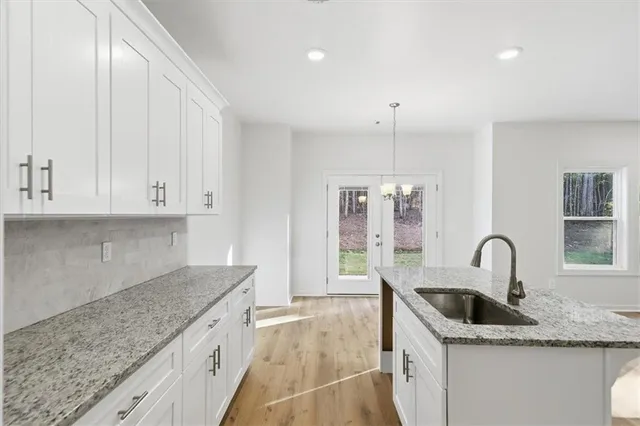 a kitchen with granite countertop a sink and white cabinets