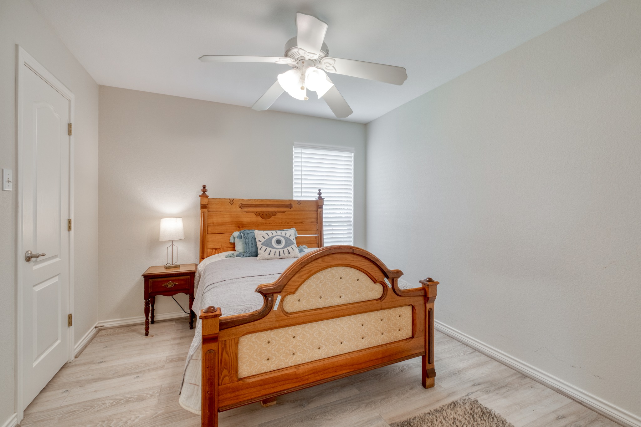 341 Brown Road McDade, TX 78650 - Photo 24 of 38 A well-lit room showcases durable laminate flooring, a classic wooden bed frame, and a functional ceiling fan with lighting.