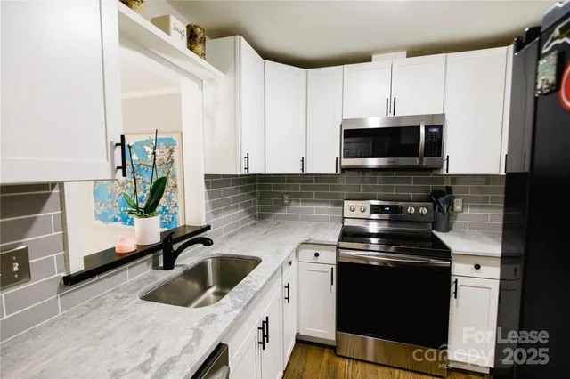 a kitchen with stainless steel appliances a sink a stove a microwave a sink and cabinets