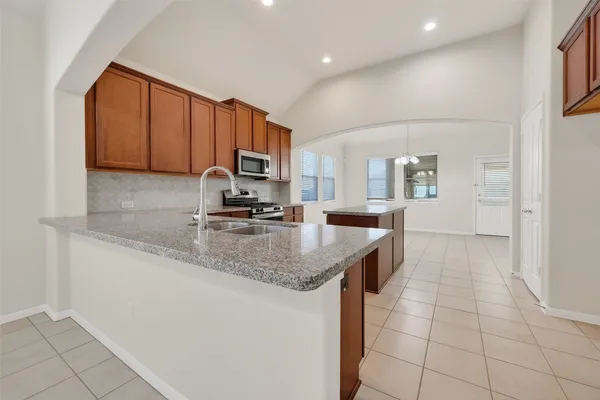 a kitchen with stainless steel appliances granite countertop a stove a sink and a microwave