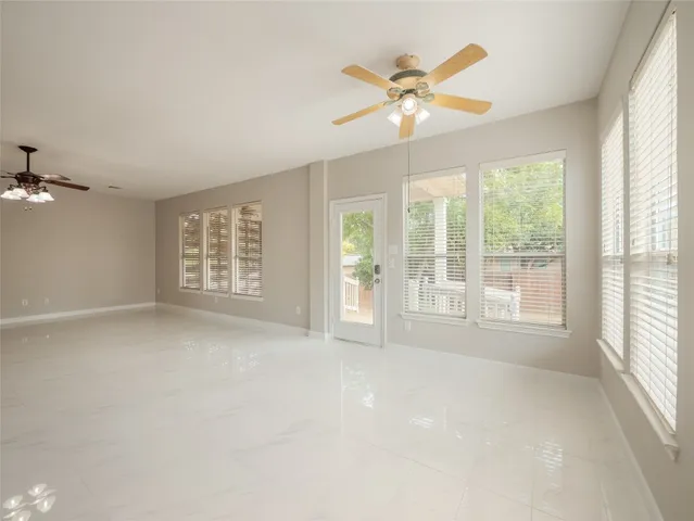 an empty room with windows and chandelier fan
