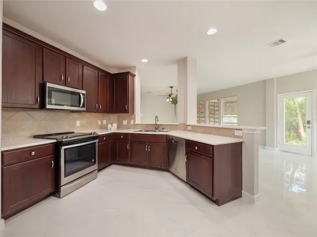 a kitchen with stainless steel appliances granite countertop wooden cabinets a stove a sink and a microwave