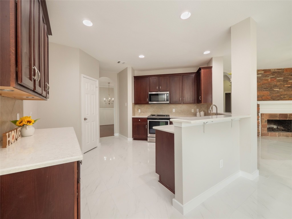 406 Primavera Loop Kyle, TX 78640 - Photo 15 of 38 a kitchen with kitchen island granite countertop a sink a stove and a refrigerator