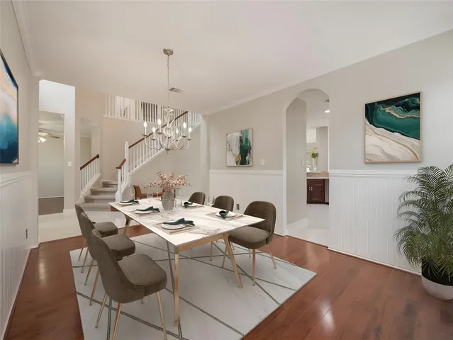 a dining room with wooden floor a chandelier a glass table and chairs