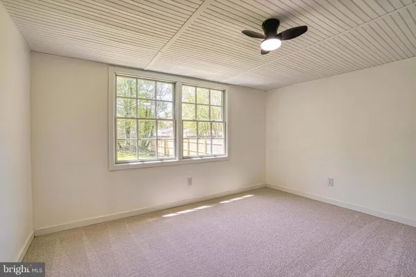 an empty room with a ceiling fan and window