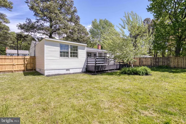 a backyard of a house with wooden fence and large trees